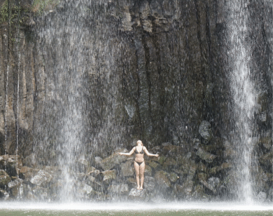 Woman standing on rocks in a waterfall.