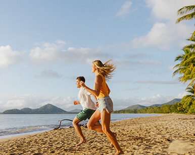 Happy couple running down a North Queensland beach.