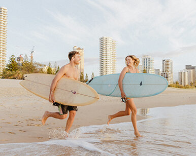 Photo of a young couple with surfboards on Surfers Paradise Beach.