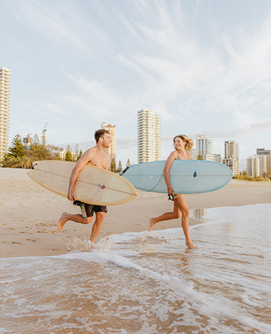 Photo of a young couple with surfboards on Surfers Paradise Beach.
